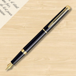 Stylo plume Waterman Hémisphère noir et doré photographié sur un bureau en bois clair.